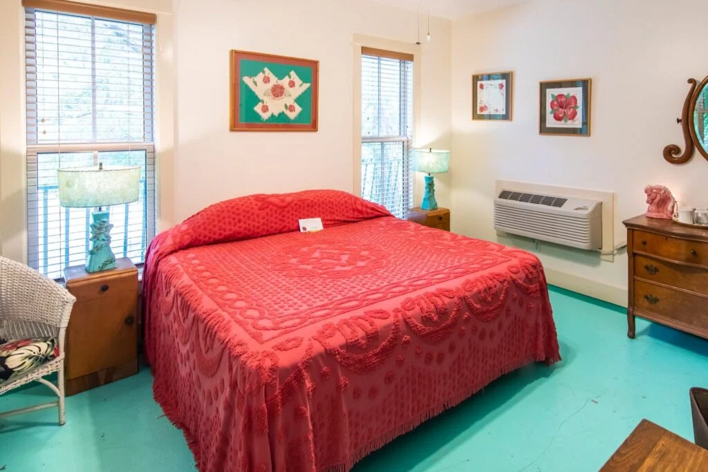 The bed in our signature Hibiscus Room. Around the bed are framed pictures of vintage hibiscus prints and textiles