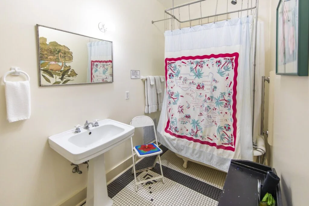The Hibiscus Room clawfoot tub and shower, surrounded by a beautiful old florida shower curtain.